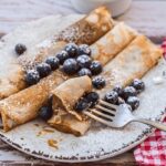 Crepes Vegane sottili e dorate, servite con frutta fresca e sciroppo d'acero