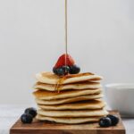 Pancake vegani soffici serviti con sciroppo d'acero e frutta fresca.