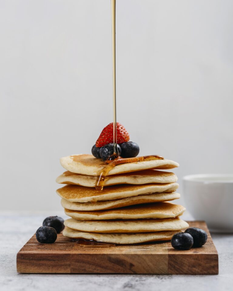 Pancake vegani soffici serviti con sciroppo d'acero e frutta fresca.