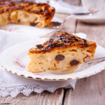 Torta di mele cremosa appena sfornata, guarnita con mele fresche e zucchero a velo