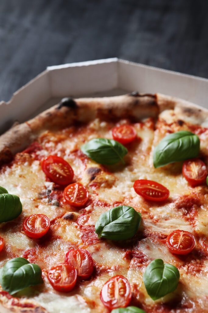 Pizza Margherita Napoletana appena sfornata, guarnita con pomodori freschi, mozzarella di bufala e basilico