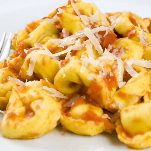 Tortellini al sugo serviti con parmigiano e basilico