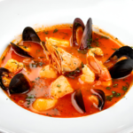 Zuppa di Pesce alla Napoletana con frutti di mare, pomodori e basilico fresco in una ciotola rustica