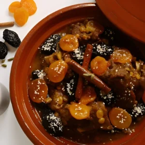 Tajine di agnello con prugne e mandorle, servita in un piatto di terracotta tradizionale marocchino